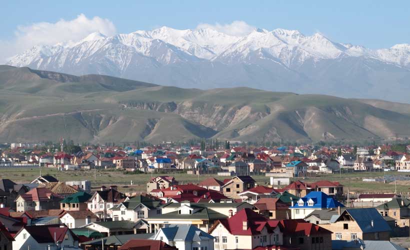Kyrgyzstan Village with snow capped mountains in the background