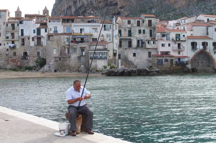 Man sitting fishing by the water Pantelleria