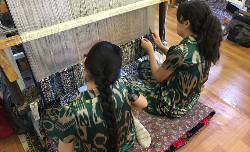 Two girls making intricate carpet in Bukhara